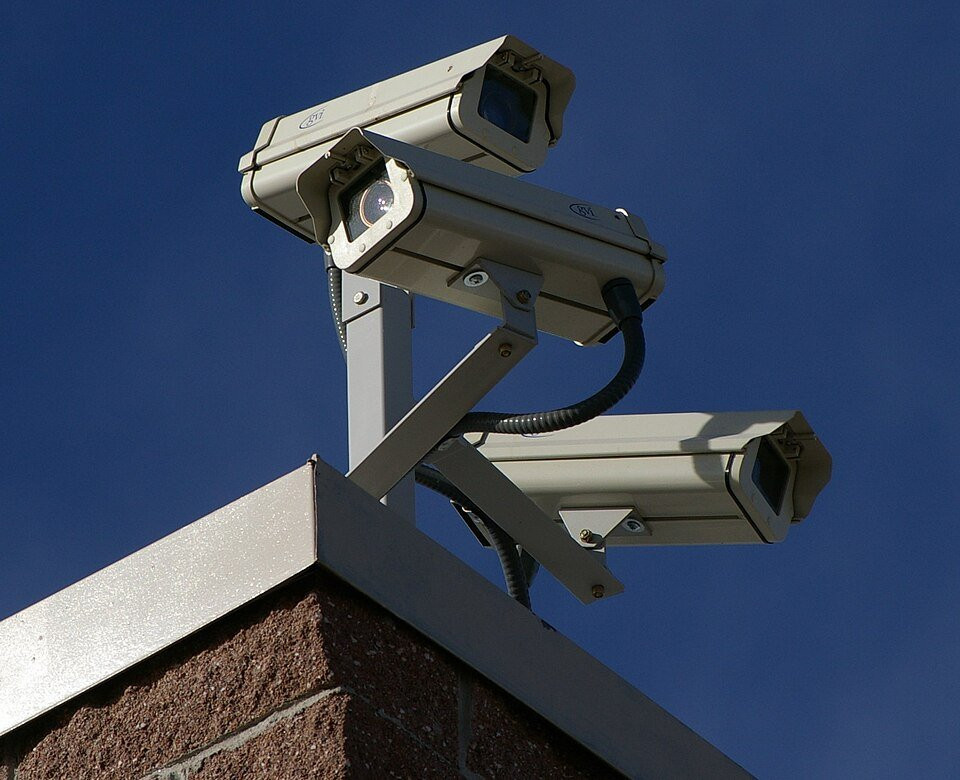 Three surveillance cameras overlooking a site, representing physical security monitoring.