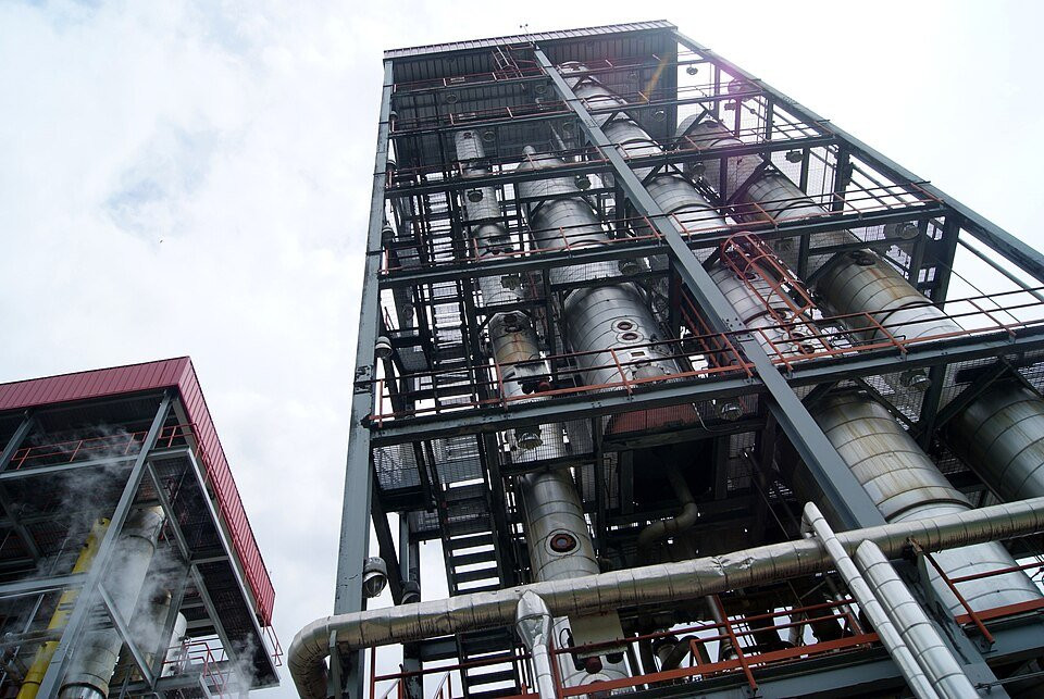 Tall industrial distillation columns with access platforms and connecting pipework.