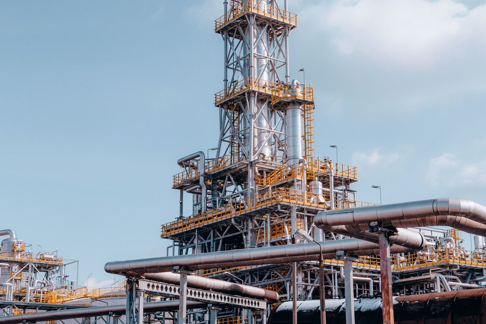 Oil refinery with process towers and connected pipework.