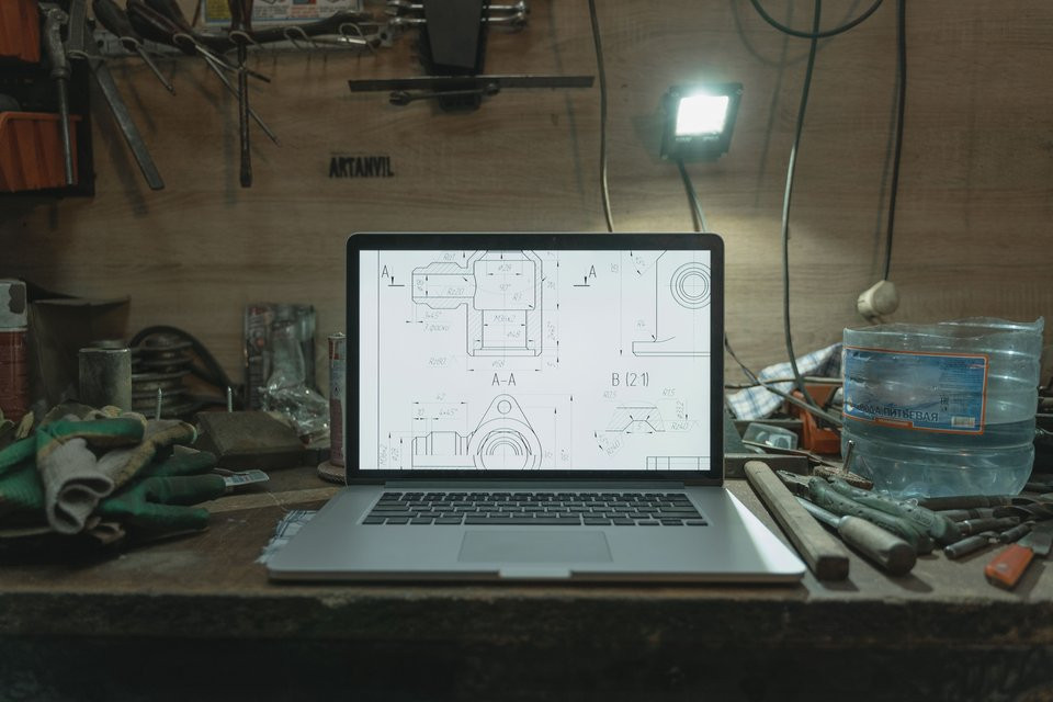 Laptop displaying technical drawings on a workshop bench.