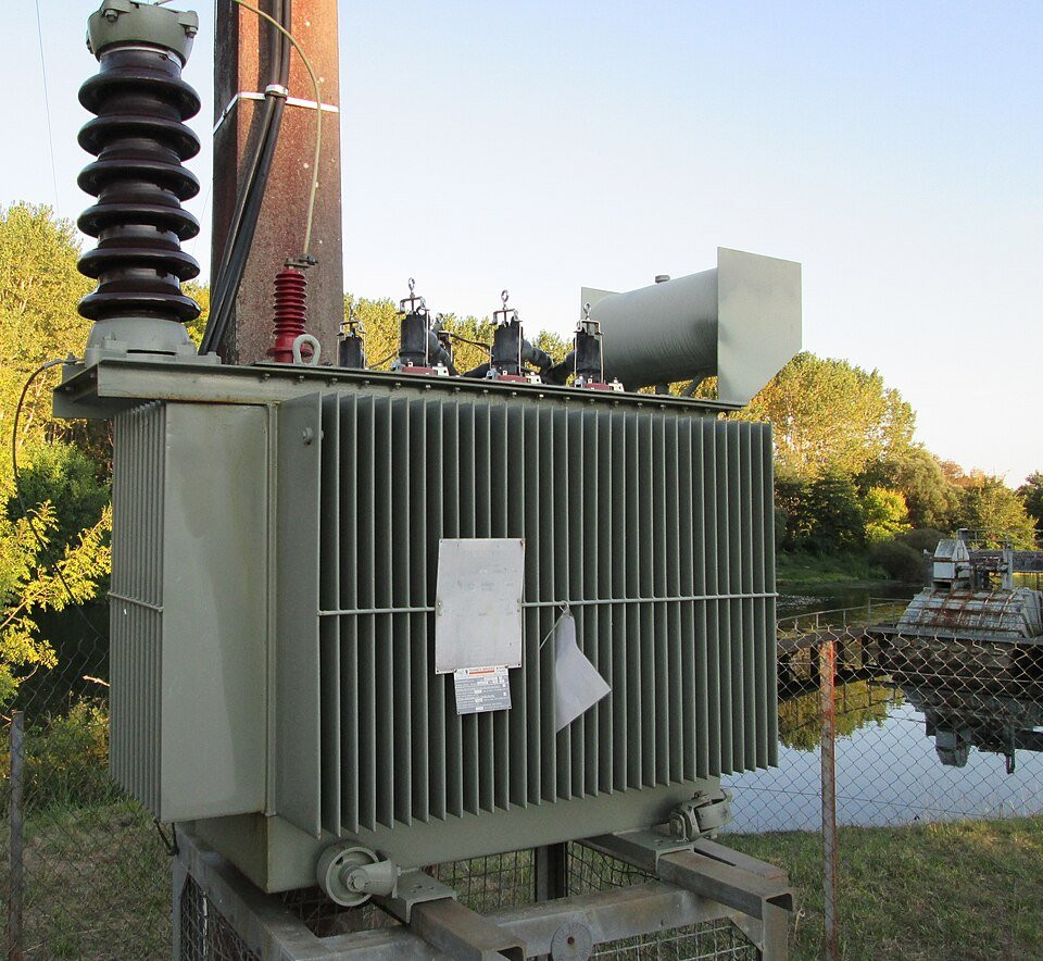 Industrial electrical power transformer showing its cooling fins and connections.