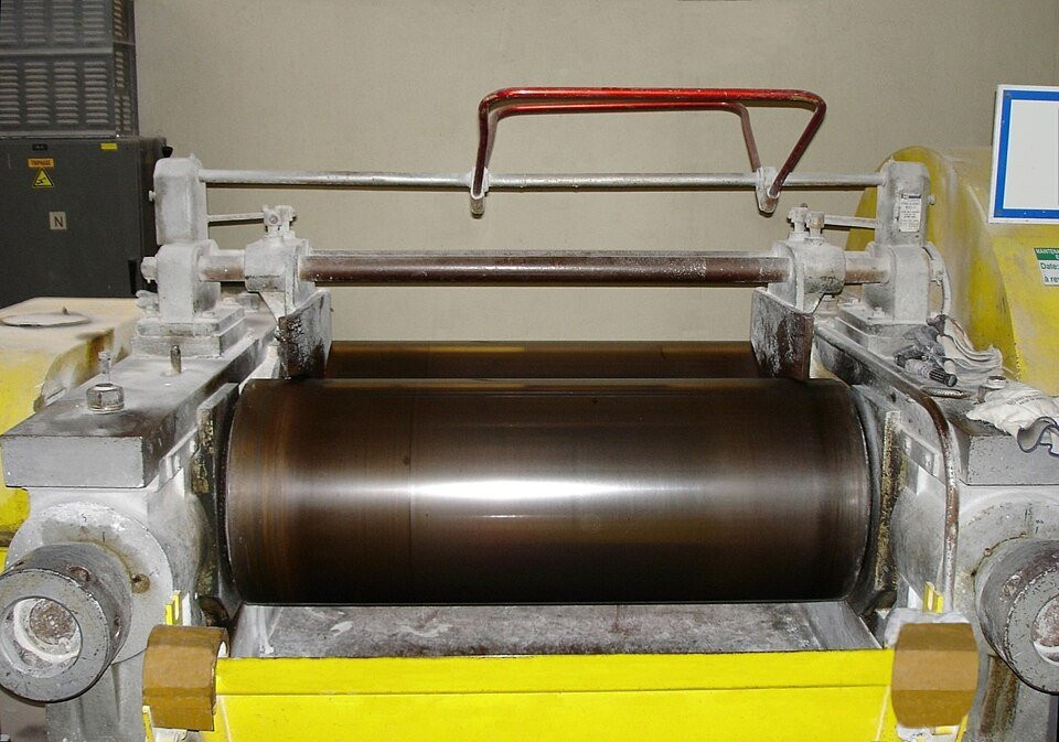 The rollers of a calender machine used to process synthetic rubber.