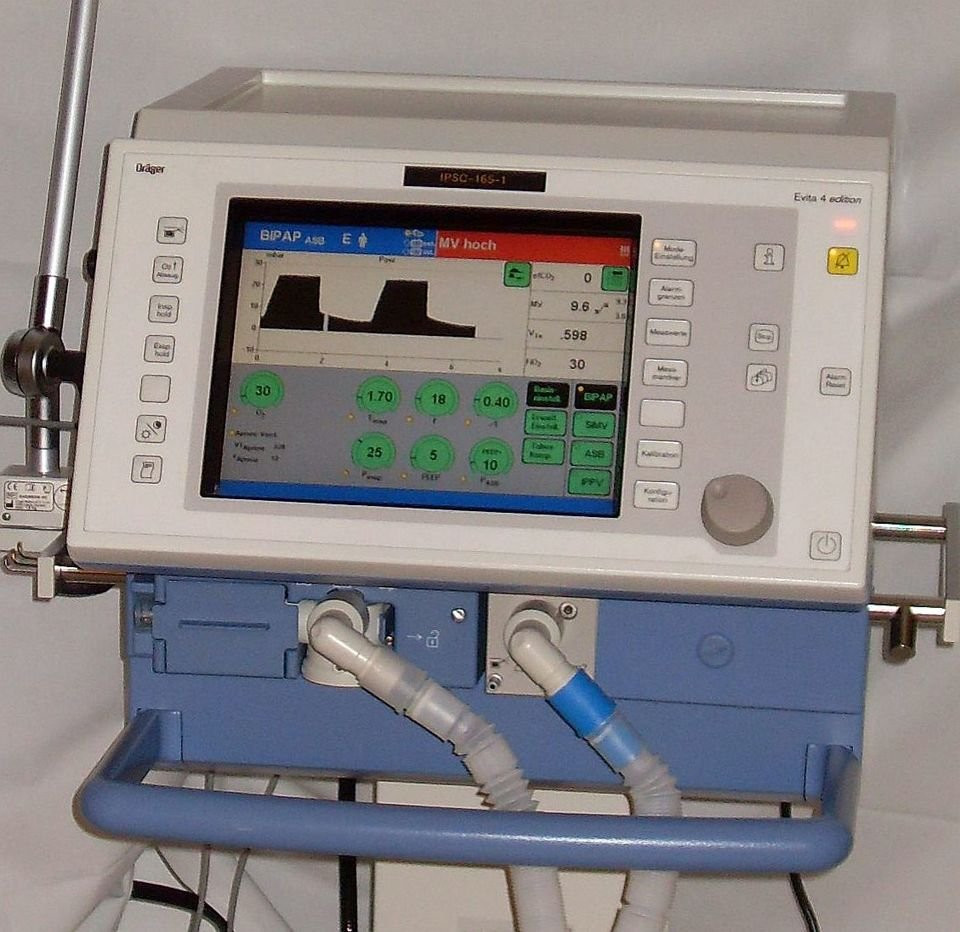 An intensive-care ventilator with breathing circuits and a waveform display.