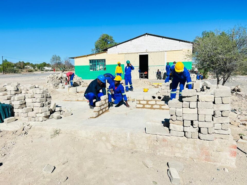 Brickwork practice structures in a Namibian construction learning area, illustrating masonry bonds and wall construction.