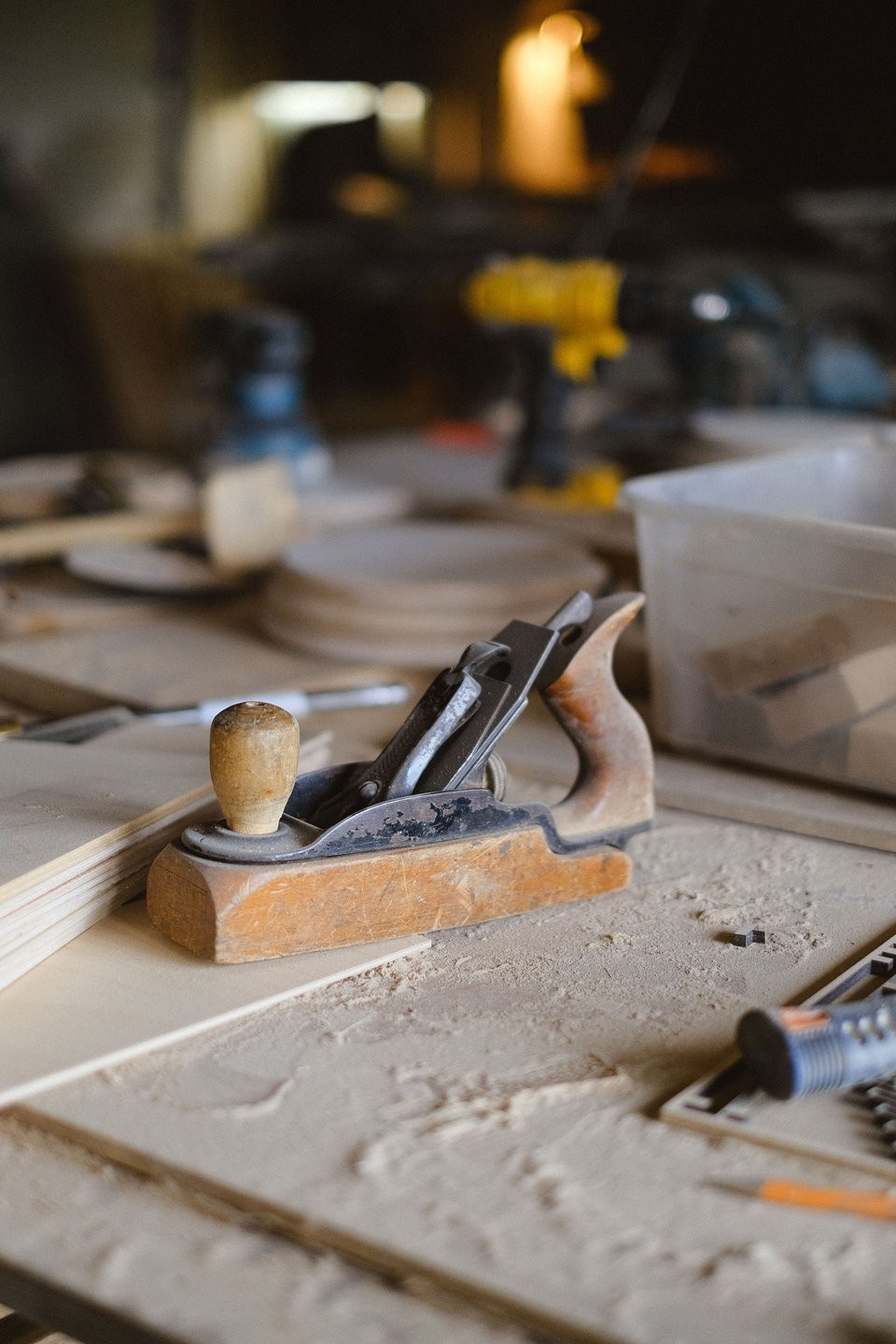 Hand plane on a timber workbench with joinery equipment in the background.