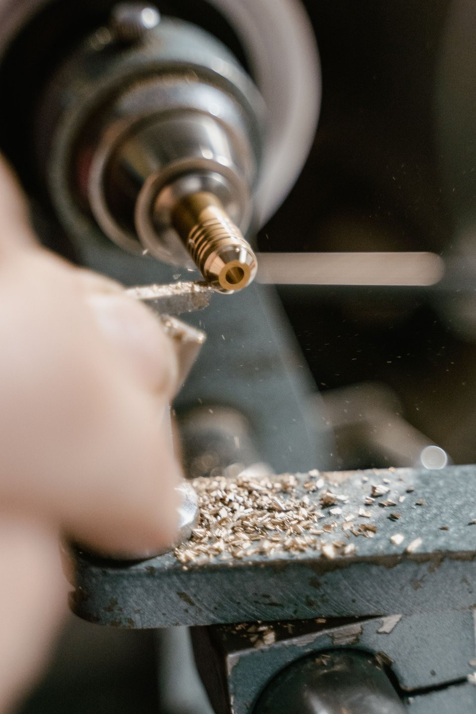 A small brass component being turned on a precision lathe.