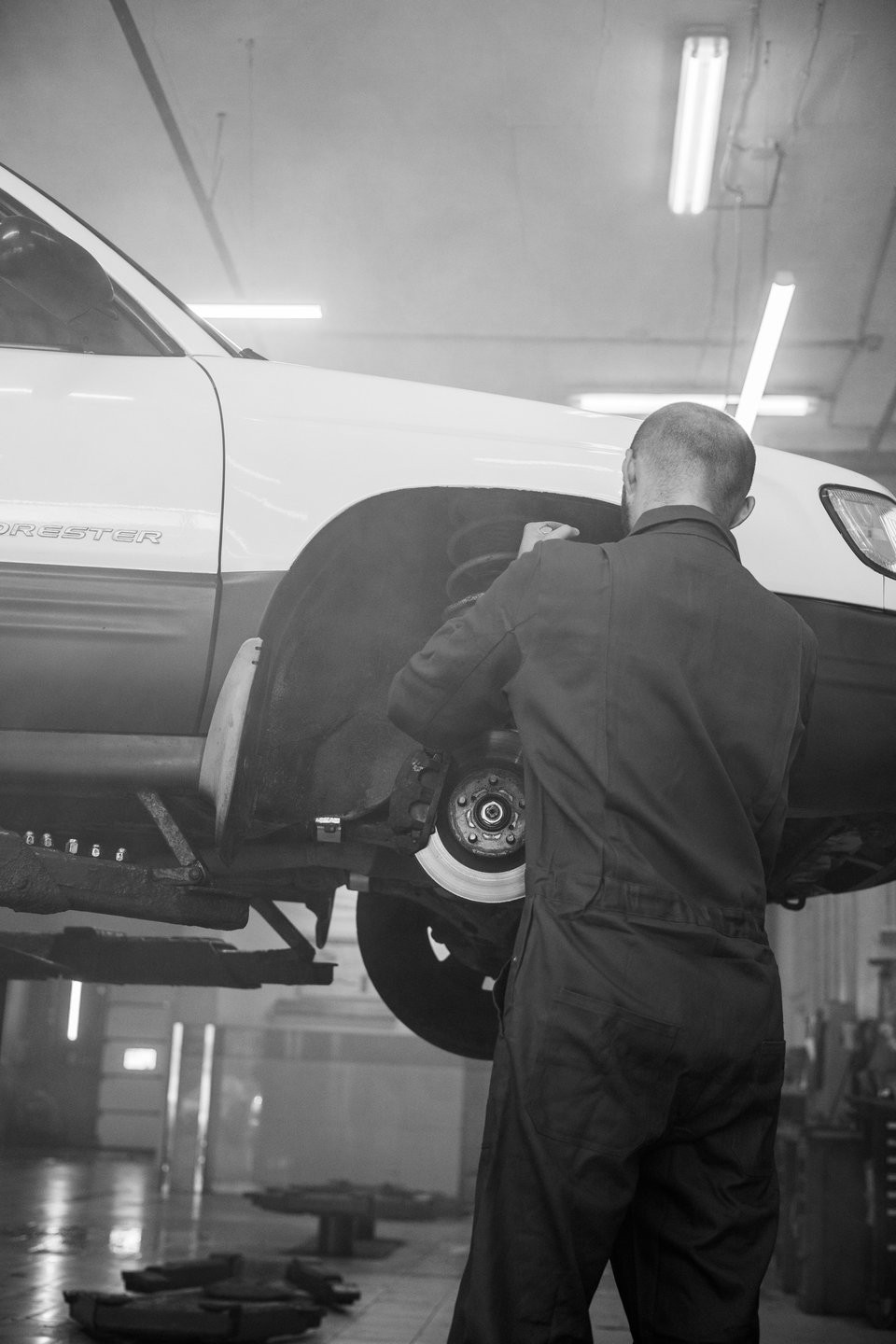 A mechanic works on a vehicle brake assembly in a workshop.