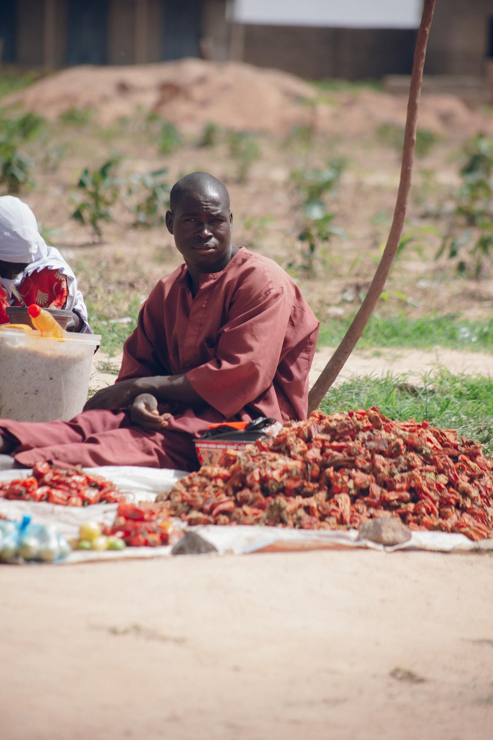 Market trader seated beside a clearly arranged produce display.