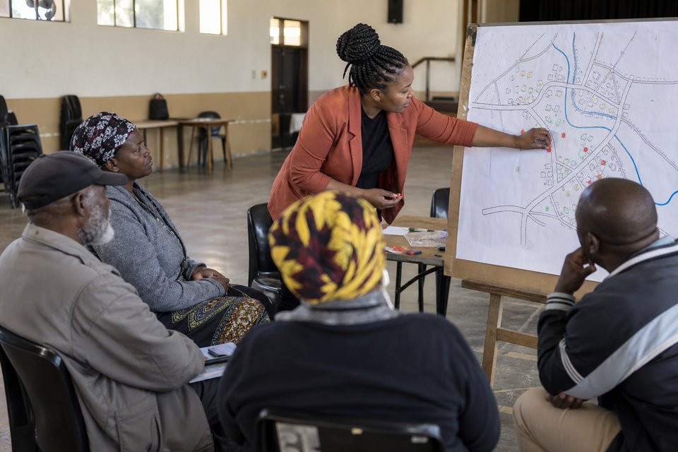 An education researcher discusses a school-access map with community members.